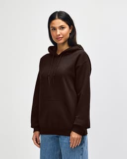 A brown hooded sweatshirt with a kangaroo pocket and a logo. The model is standing against a plain white background.