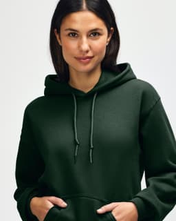 A green hooded sweatshirt worn by a woman with long hair, featuring a hood and a logo.