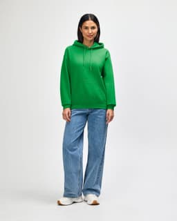 A green hooded sweatshirt with a front pocket and drawstring, worn with blue jeans and white sneakers.