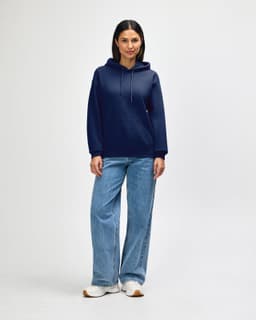 A navy blue Gildan Heavy Blend adult hooded sweatshirt worn by a model with jeans and sneakers. The sweatshirt features a hood and pockets.