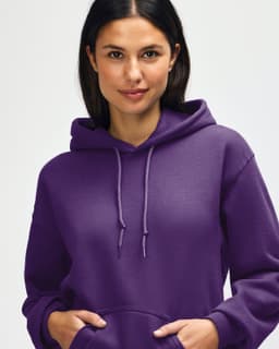 A purple hooded sweatshirt is being worn by a young man, who is pulling the hood over his head.