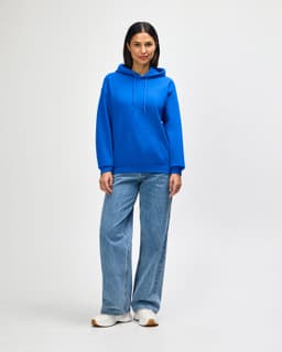 A blue hooded sweatshirt paired with jeans, featuring a front pocket and drawstring hood, modelled by a woman.