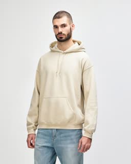A light beige hooded sweatshirt with a front pocket and drawstrings, worn by a model. The garment has a logo.