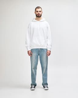 A white hooded sweatshirt worn by a young man, paired with black jeans and sneakers. The sweatshirt features a logo.