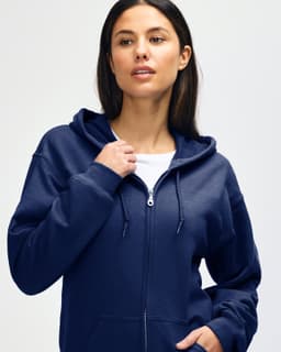 A model is wearing a navy blue Gildan Heavy Blend adult full zip hooded sweatshirt with black pants and sneakers.