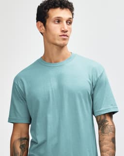 A unisex short sleeve t-shirt in a soft turquoise colour, featuring a logo on one side.