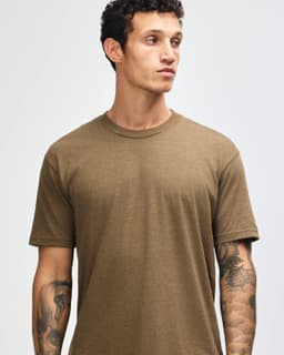 A unisex short sleeve t-shirt in a muted brown colour, displayed on a model. Features a logo.