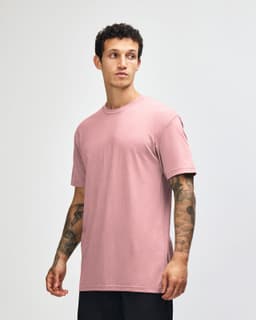 A unisex short sleeve T-shirt in soft pink, featuring a relaxed fit and a logo on the brand label.