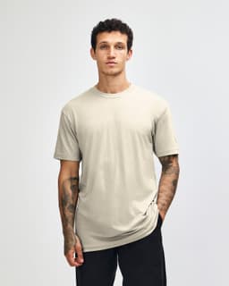 A unisex short sleeve T-shirt in a neutral beige colour, displayed on a model. It features a simple design and logo.