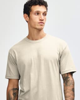 A unisex CVC short sleeve t-shirt in a light beige colour, featuring a simple design and a logo.