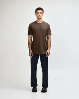 A unisex short sleeve T-shirt in brown, displayed by a model, paired with dark cargo pants and footwear.