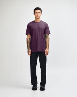 A unisex short sleeve T-shirt in a deep purple colour, paired with black cargo pants, featuring a logo.