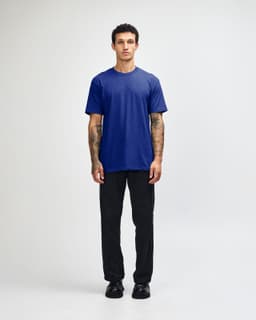 A unisex short sleeve t-shirt in blue, paired with black cargo pants, displayed on a model.