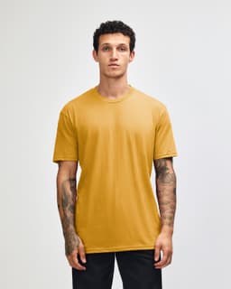 A unisex short sleeve t-shirt in a vibrant mustard colour, displayed on a model. It has a simple design and includes a logo.