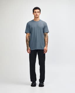 A short sleeve unisex t-shirt in a blue shade, paired with black cargo pants, featuring a logo.