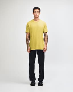 A unisex short sleeve t-shirt in yellow, paired with dark cargo pants and sneakers, worn by a standing model.