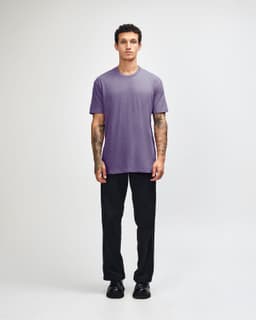 A unisex short sleeve T-shirt in purple, paired with black cargo pants. It features a logo on the shirt.