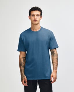 A unisex short sleeve t-shirt in a blue shade, displayed on a model with straight posture. Features a logo.