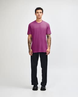 A unisex short sleeve T-shirt in vibrant pink, paired with relaxed black pants and a casual stance.