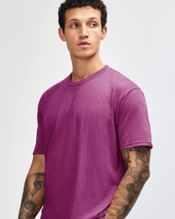 A unisex short sleeve t-shirt in a vibrant magenta colour, worn by a model with a neutral expression.