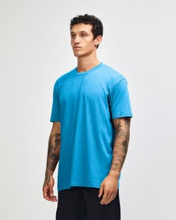 A model wearing a blue unisex short sleeve t-shirt, displaying a simple design and a relaxed fit.