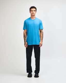 A unisex CVC short sleeve t-shirt in bright blue, worn with black cargo pants, featuring a casual style.