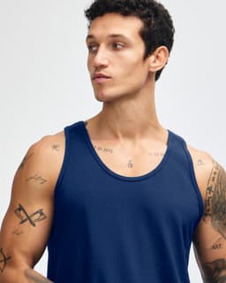 A model wearing a navy blue unisex fine jersey tank top, showcasing a relaxed fit and sleeveless design.