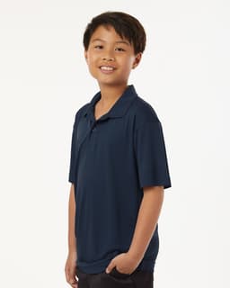 A youth performance polo in navy blue, featuring a collar and short sleeves, worn by a smiling boy.