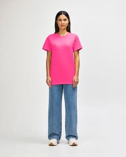 A model wearing a bright pink Gildan Heavy Cotton adult T-shirt paired with black pants and sneakers.