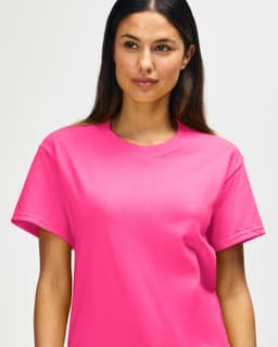 A pink Gildan Heavy Cotton Adult T-Shirt on a model, featuring a plain design and a brand logo.