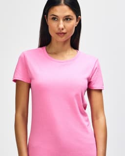 A pink Gildan Heavy Cotton Ladies' T-Shirt displayed on a smiling woman, featuring a simple design and a logo.
