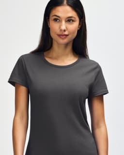 A grey Gildan Heavy Cotton Ladies' T-Shirt displayed on a smiling woman, featuring a simple design and soft fabric.
