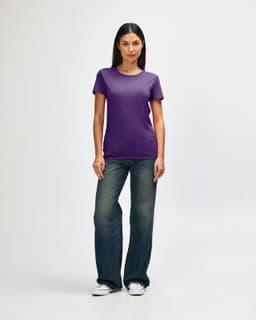 A purple Gildan Heavy Cotton Ladies' T-Shirt displayed on a model paired with blue jeans and white sneakers.