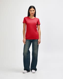 A red Gildan Heavy Cotton Ladies' T-Shirt displayed on a model wearing blue jeans and white sneakers, with a logo present.