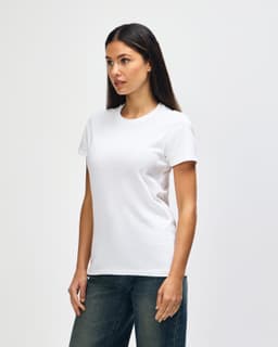 A white Gildan Heavy Cotton Ladies' T-Shirt displayed on a model, paired with blue jeans. The shirt has a simple design and a logo.