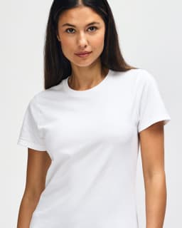 A white Gildan Heavy Cotton Ladies' T-Shirt displayed on a model, featuring a simple design and a logo.