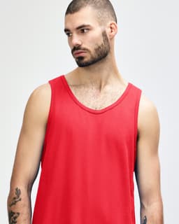 A red Gildan Heavy Cotton adult tank top displayed on a model with short, curly hair and a neutral background.