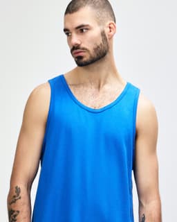 A blue Gildan Heavy Cotton adult tank top displayed on a model. The tank has a round neckline and no visible branding.