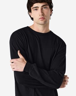 A model wearing a long sleeve t-shirt in black, featuring a logo on the sleeve.