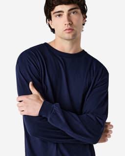 A model wearing a navy long sleeve T-shirt with a relaxed fit and a logo on the sleeve.