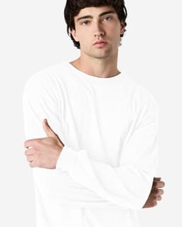 A white long sleeve T-shirt on a model with a neutral background, featuring a logo on the sleeve.