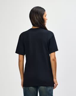 A black Gildan Softstyle adult t-shirt, featuring a simple design and a logo on the back. The model is facing away.