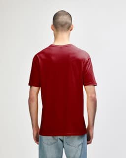 A red Gildan Softstyle adult T-shirt displayed from the back, worn by a model in denim jeans.