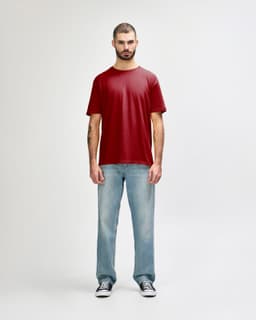 A model wearing a red Gildan Softstyle adult t-shirt paired with light blue jeans and white shoes. The shirt has a logo.