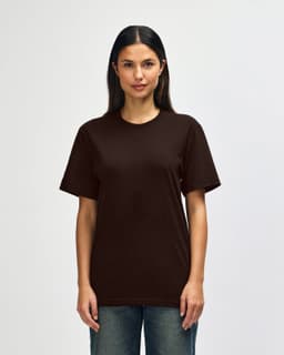 A man is wearing a brown Gildan Softstyle adult t-shirt, featuring a plain design. The shirt has a logo on it.