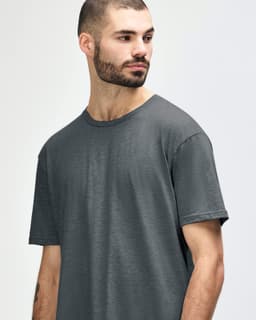 A model wearing a Gildan Softstyle adult t-shirt in dark grey with a round neckline and short sleeves.