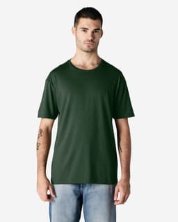 A man wearing a dark green Gildan Softstyle adult t-shirt, paired with light blue jeans. The shirt has a logo.
