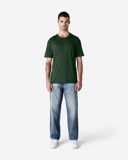 A green Gildan Softstyle adult T-shirt displayed on a model, paired with blue jeans and white shoes.