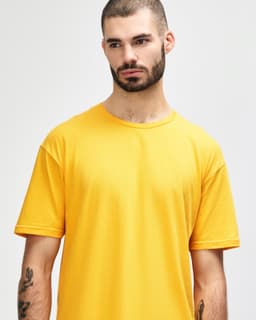 A smiling young man wearing a vibrant yellow Gildan Softstyle adult t-shirt with a logo on it.