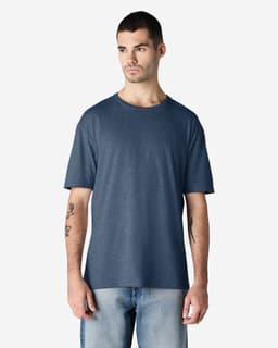 A man wearing a navy blue Gildan Softstyle adult t-shirt stands against a plain background. The shirt has a logo.